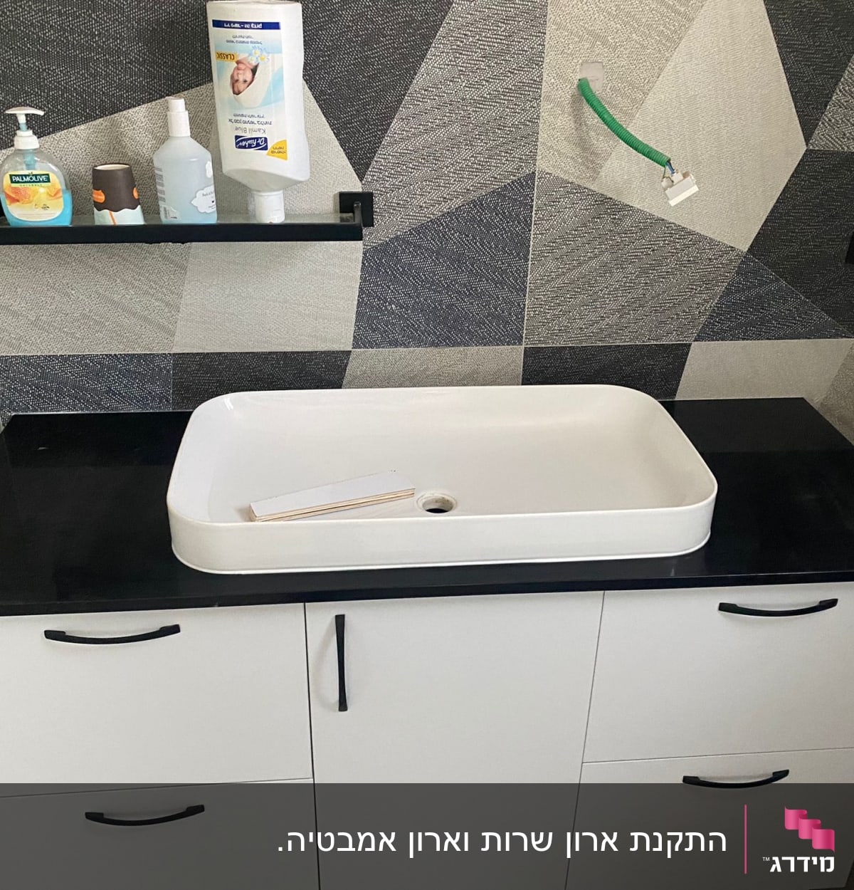 כיור לבן על ארון שחור עם ידיות